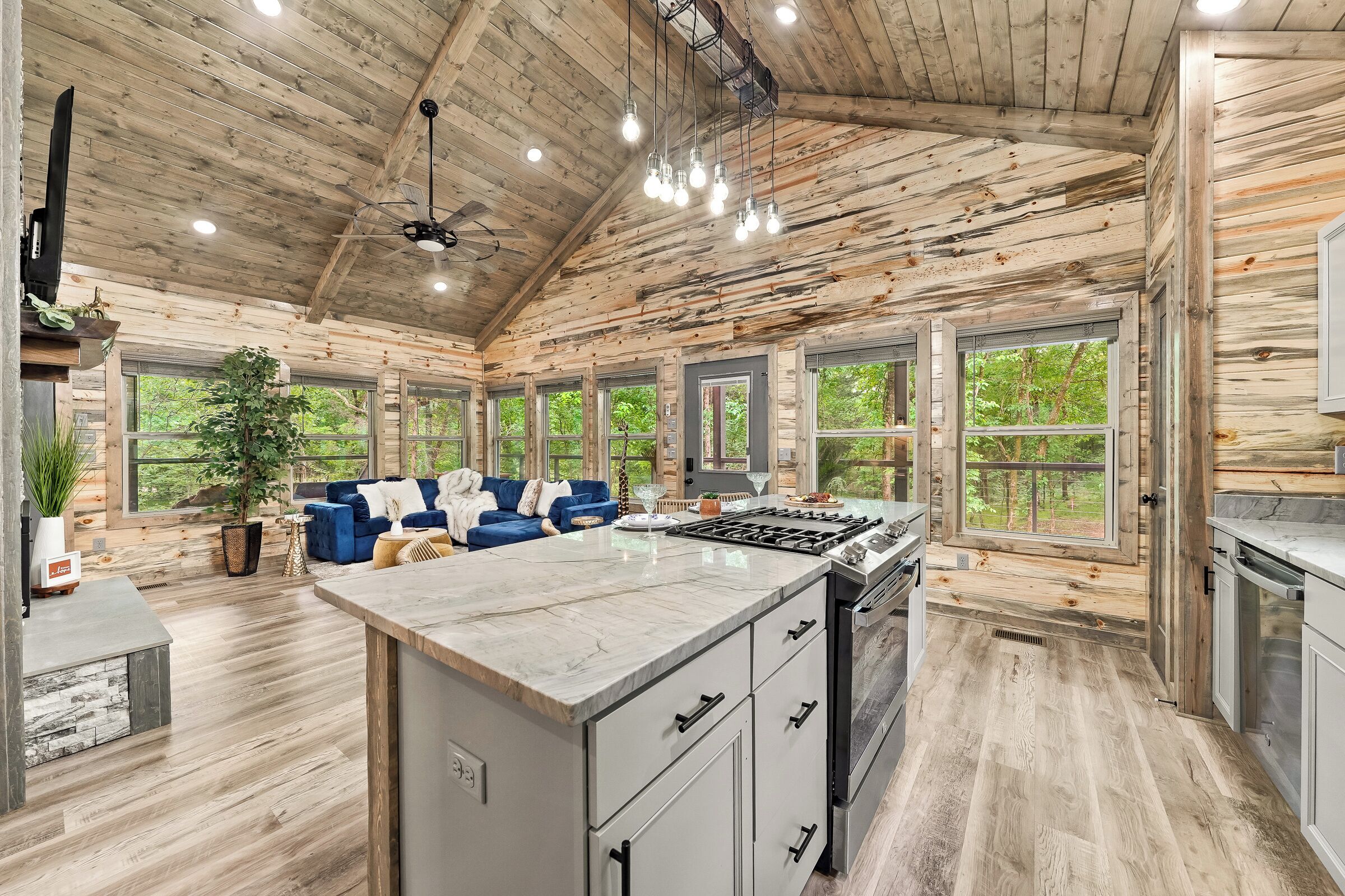 Una cocina espaciosa con una isla grande, techo de madera y amplios ventanales que ofrecen vistas al exterior.