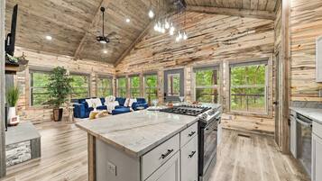 Una cocina espaciosa con una isla grande, techo de madera y amplios ventanales que ofrecen vistas al exterior.