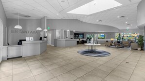 A spacious lobby with a reception desk, seating area, and a large window providing natural light.