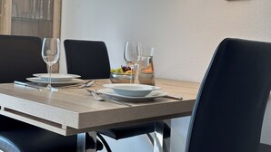 Une table à manger dressée avec des assiettes, des verres et des couverts, agrémentée d’un panier de fruits et d’un chandelier.