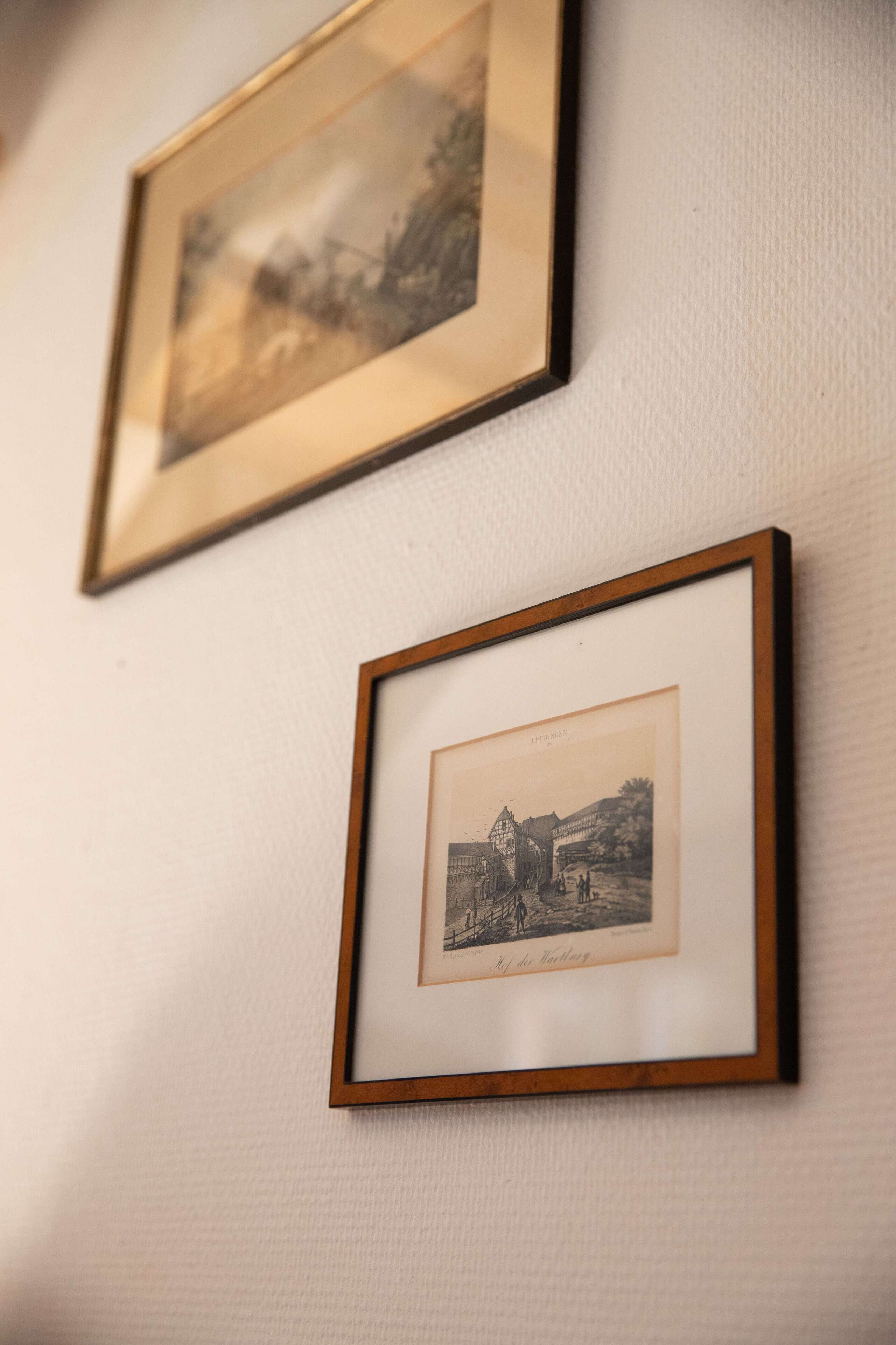 Two framed black and white photographs on a textured wall.