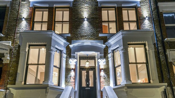 A multi-story building with a central entrance, a staircase leading up to it, and a checkered tile pattern on the steps.