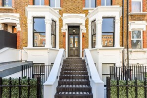 A multi-story building with a central entrance, a staircase, and a gated entrance. - Studio 9 @ OneStay Maida Vale (London)