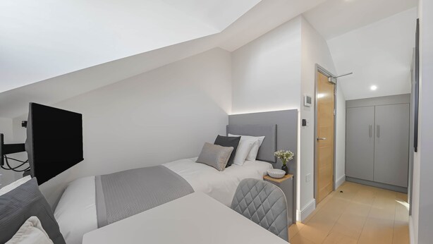 A modern, compact bedroom with a bed, bedside table, and a TV mounted on the wall. - Studio 18 @ OneStay Maida Vale, Studio 18 at One Stay (London)