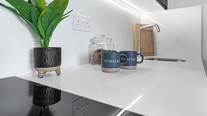A modern kitchen with a white countertop, a potted plant, a glass jar, and two mugs with the text 'onestay.' - Studio 20 @ OneStay Maida Vale (London)