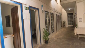 A corridor with doors, a potted plant, and a table with a bottle. - Suite Confort 201 (Centro Diamantina)