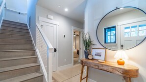 Un escalier menant à une chambre, une table de chevet avec une lampe et un miroir qui reflète une fenêtre.
