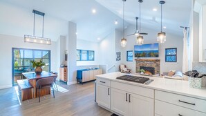 Une cuisine moderne dotée d’un grand îlot central, de luminaires suspendus et d’une cheminée.