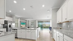 Una cocina moderna con armarios blancos, encimeras de granito y una isla grande.
