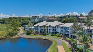A resort with multiple-story buildings, a swimming pool, and a natural lake.
