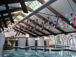 An indoor swimming pool with multiple lanes, a diving platform, and a ceiling with wooden beams and green glass panels. - Valley Lodge 37 (Gunnislake)
