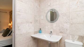 A bathroom with a white sink, a toilet, and a mirror with a mosaic border.