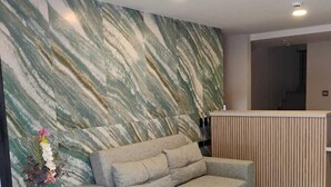 Una sala de estar moderna con un sofá gris, una mesa redonda de madera y un jarrón decorativo con flores.