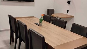 Un salón de conferencias con una larga mesa, sillas, un televisor y un cactus sobre la mesa.