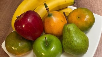 En tallrik med olika frukter, inklusive bananer, äpplen och päron, står på ett träbord.