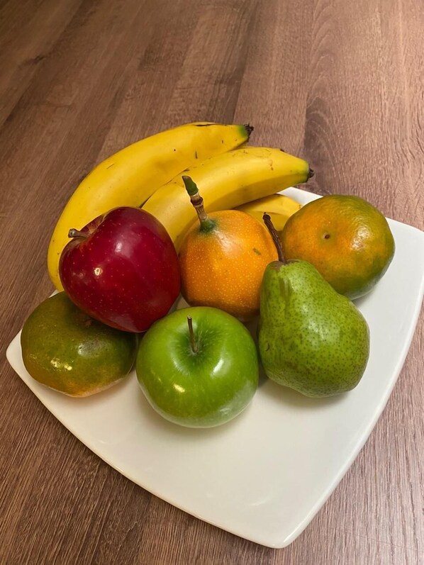 Un plato de frutas que incluye plátanos, manzanas y peras sobre una mesa de madera.