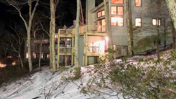 A multi-level stone house with a balcony, surrounded by trees and snow. - Slopes @ Tyro (Wintergreen Resort)