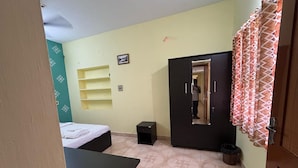 Une chambre à coucher comprenant un lit, une armoire, une petite table et une étagère.