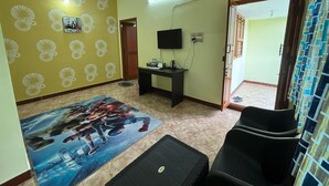 Un salon avec un canapé, une table basse, un téléviseur et un tapis à motifs.