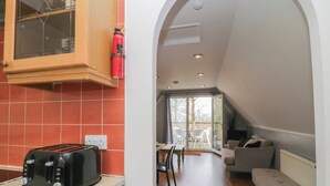 A kitchen with a toaster, a fire extinguisher, and a wooden cabinet. - Valley Lodge 38 (Gunnislake)