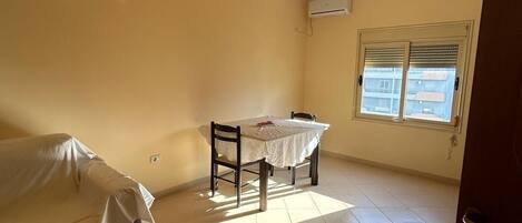 Cozy retreat with a dining table for four, a comfortable bed, and a large window with blinds.