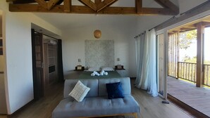 A bedroom with a bed, a sofa, a wooden ceiling, a window with curtains, and a door. - Les Longanis Sea View and Shared Pool Mont Vert (Mont Vert les Bas)