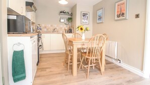Une cuisine compacte avec un coin repas, des chaises en bois, une petite table et un luminaire suspendu.
