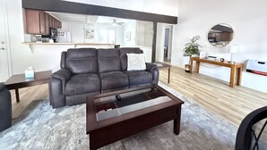 A modern living room with a leather sofa, a glass-top coffee table, and a wooden side table.