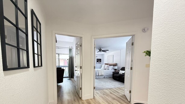 A hallway leading to a bedroom with a bed, a dresser, and a nightstand.