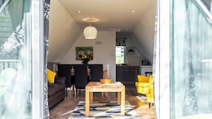 A modern interior with a dining area, a sofa, and a kitchen visible through an open door. - Valley Lodge 40 (Gunnislake)