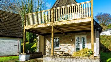 A two-story wooden structure with a balcony, stone walls, and a stone door.