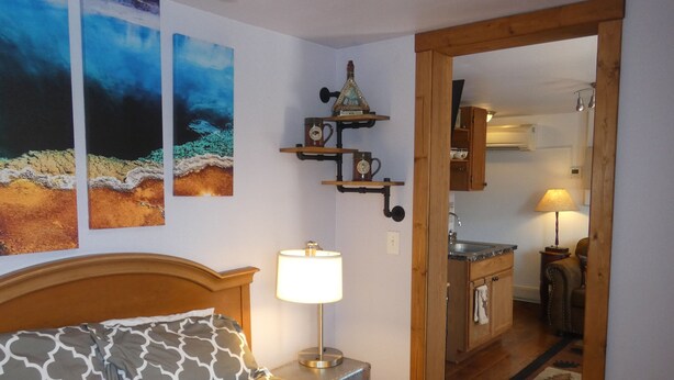 A bedroom with a patterned bedspread, a bedside lamp, and wall art.