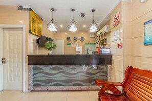 A hotel reception area with a reception desk, a plant, a clock, and a bench. - Wen Feng Hotel (Shanghai)