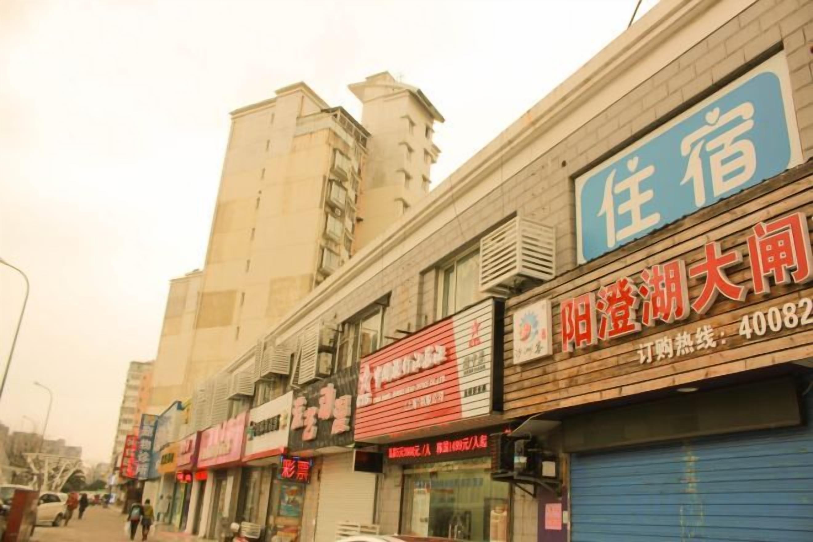 A row of commercial buildings with various storefronts, including a hotel with a blue sign.