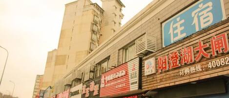 A row of commercial buildings with various storefronts, including a hotel with a blue sign.