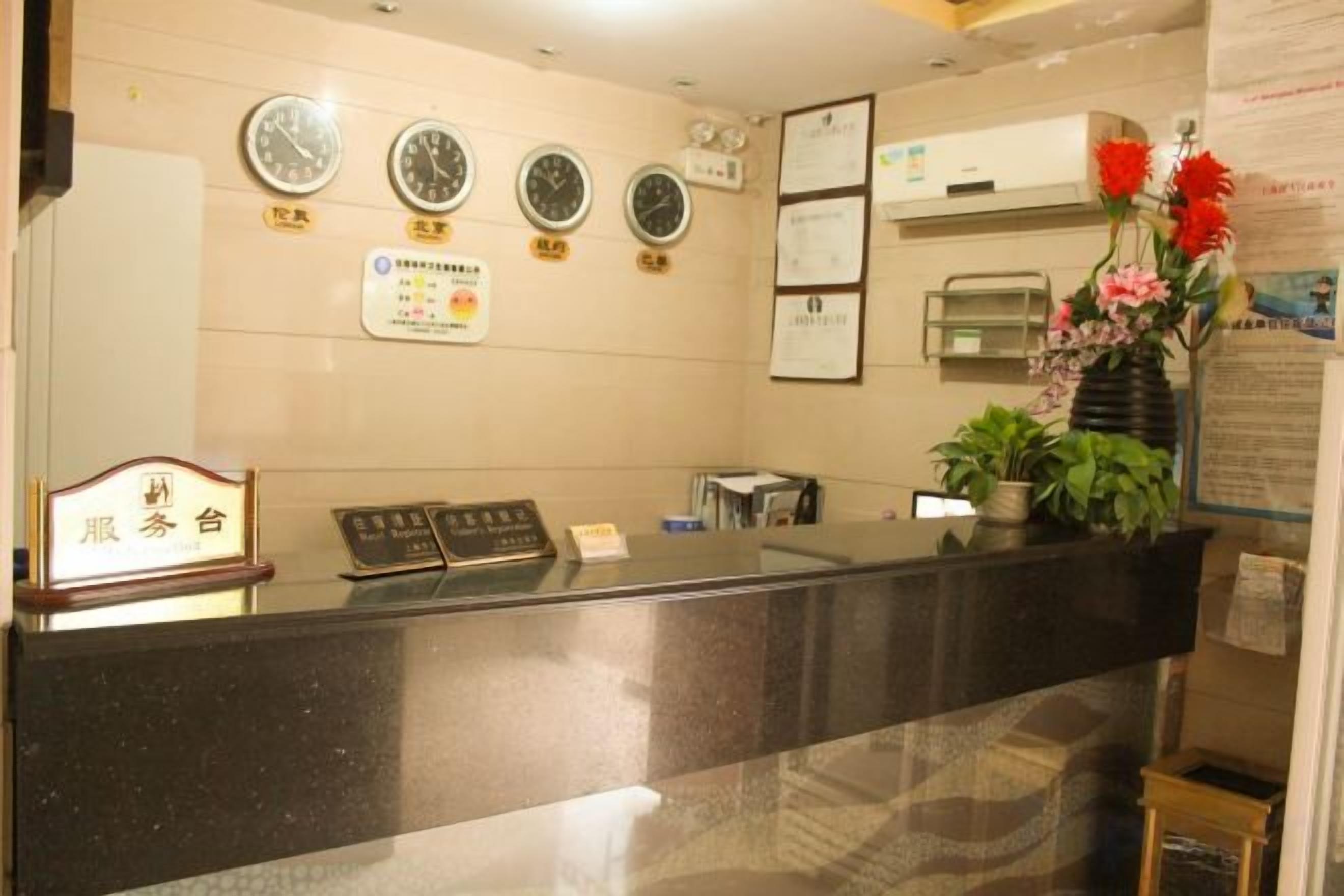 A reception desk with a clock, a bulletin board, and a potted plant.