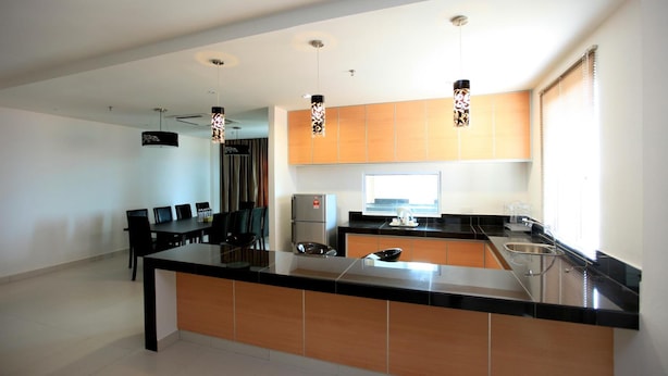 Een moderne keuken met een centraal eiland, zwarte aanrechtbladen, houten keukenkastjes en hanglampen.