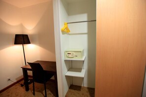 A room with a dining table, a chair, a lamp, and a shelf with a radio.