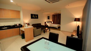 Hotelkamer met kitchenette, een bed, een bank, een eettafel met stoelen en een televisie.