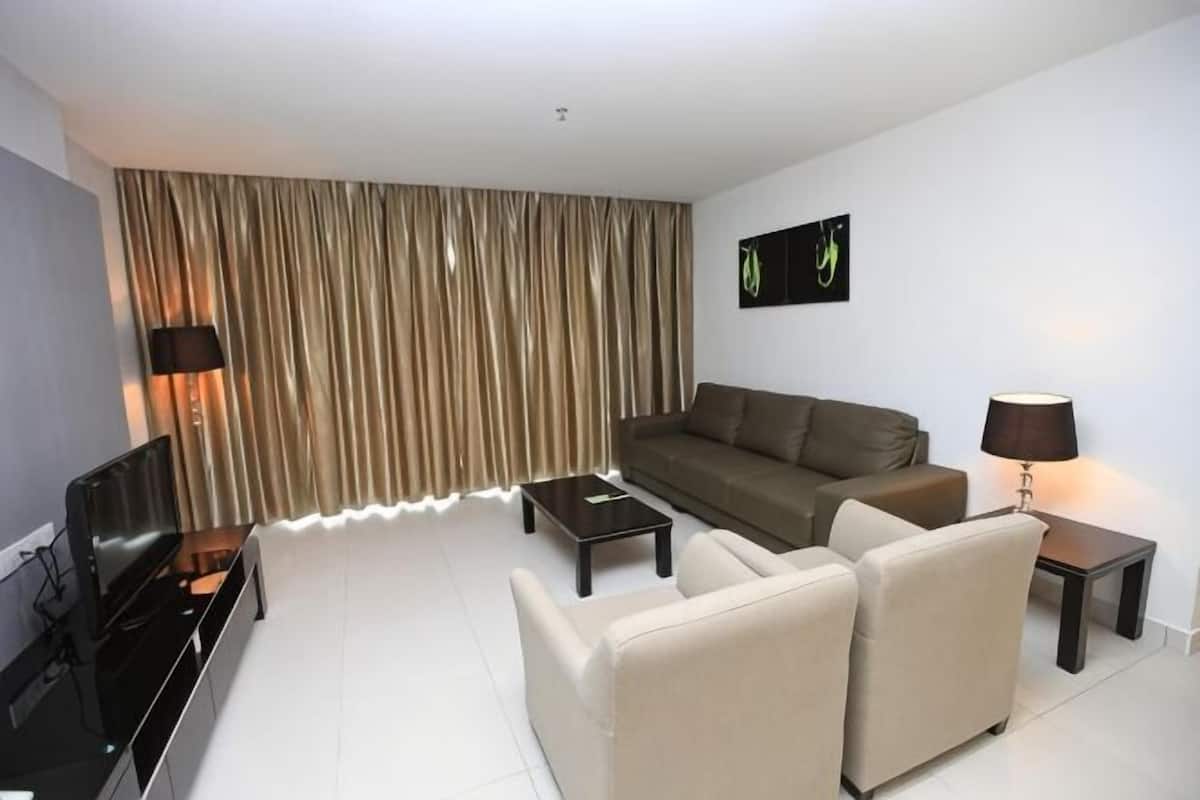 Una sala de estar con un sofá, una mesa de centro, un televisor y una lámpara.
