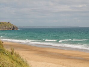 A beach with a rocky cliff and ocean waves. - 6 The Links (Penzance)