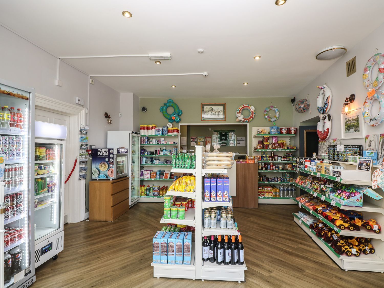 A well-lit store with refrigerated drinks, snacks, and toys.