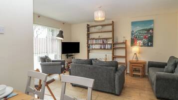 Een woonkamer met een televisie, boekenkasten en een schilderij.