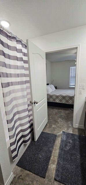 Un dormitorio con cama, cortina de ducha y puerta que da a otra habitación.
