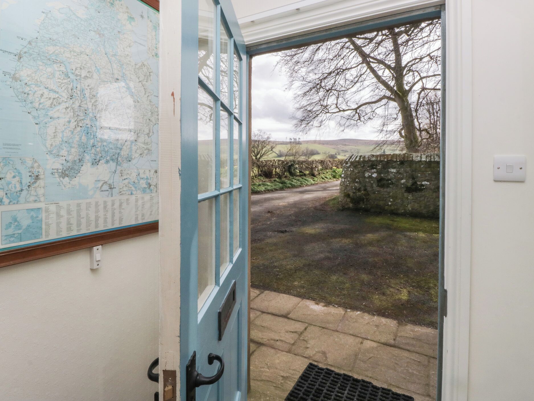 A door leading to a stone pathway with a map on the wall.