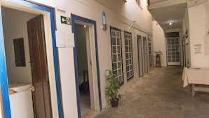A corridor with doors, a potted plant, and a table with a bottle. - Comfort Suite 101 - Acayaca Inn (Centro Diamantina)