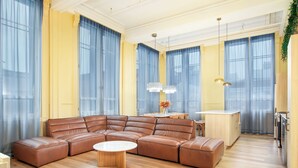 Un salon moderne avec un canapé d’angle, une table basse ronde et un coin cuisine comprenant une table à manger et des placards.