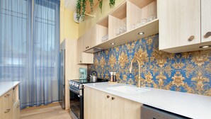 Une cuisine moderne avec des meubles en bois, une cuisinière en acier inoxydable et un dosseret à motifs bleus.
