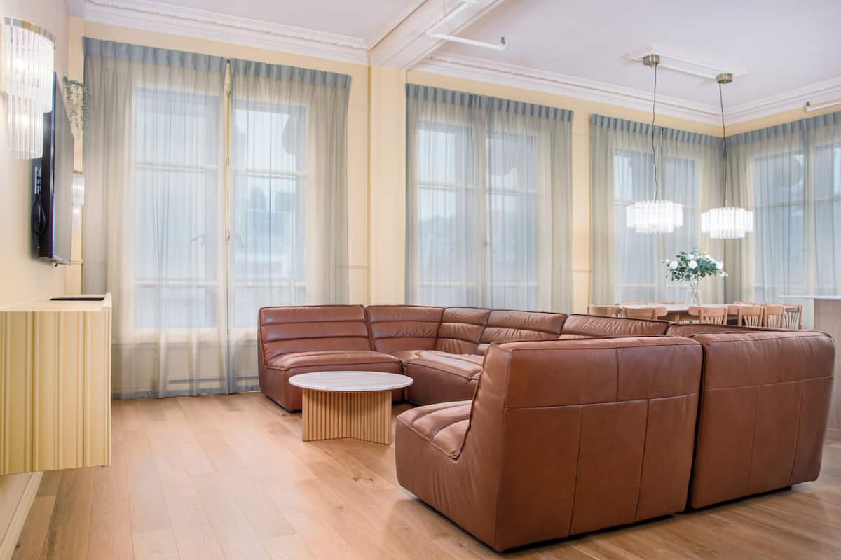 Un salón amplio con un sofá seccional en forma de L, una mesa de centro redonda y un comedor con mesa y sillas.