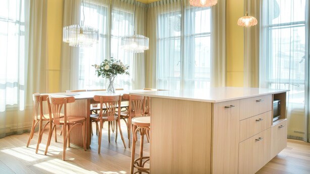 Une cuisine moderne avec un îlot central, des chaises en bois et des luminaires suspendus.